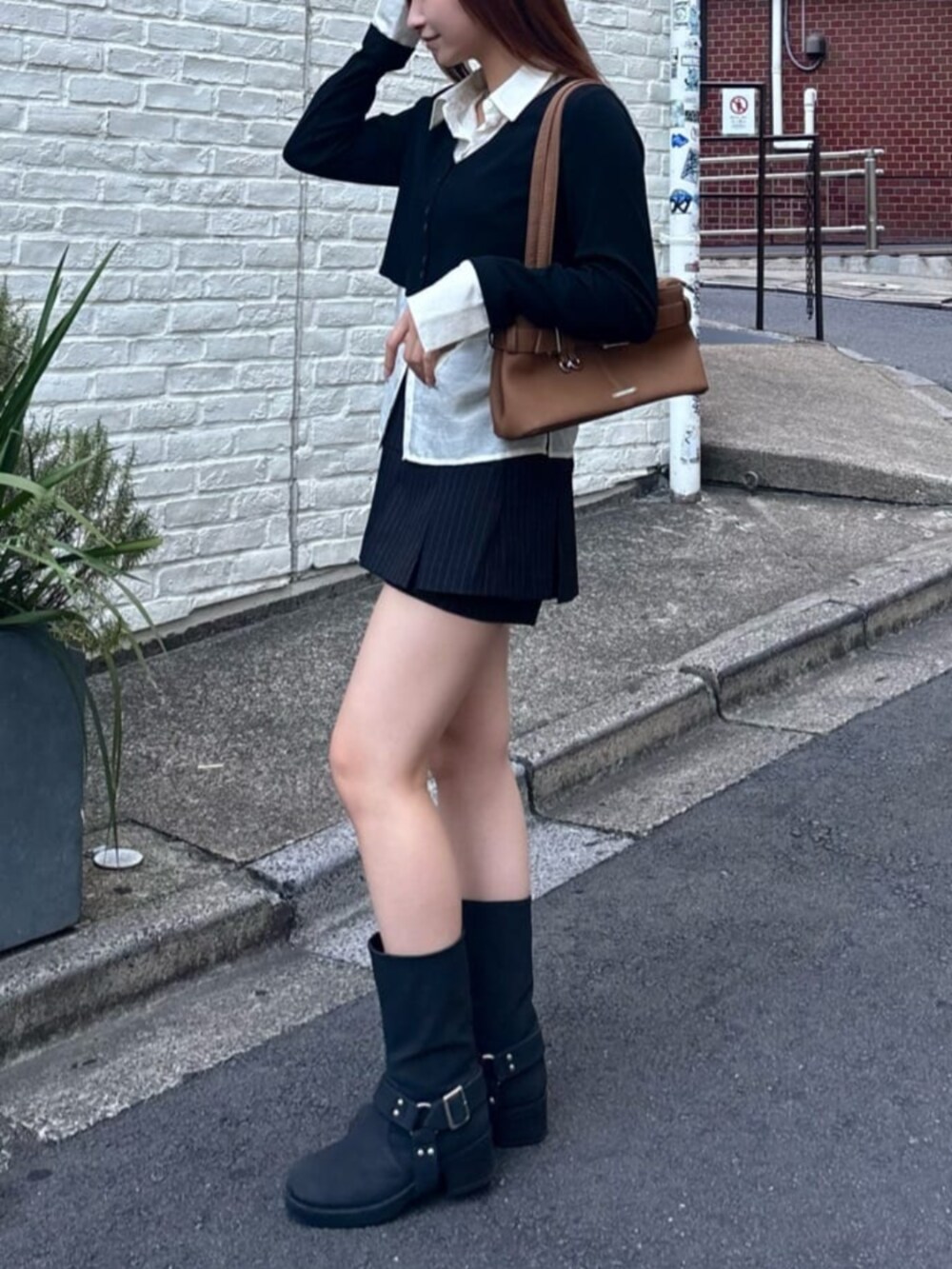 ブラック系のスカート、イエロー系のショルダーバッグ、ブラック系のブーツを着用したレディースの秋コーディネートの2枚目の写真