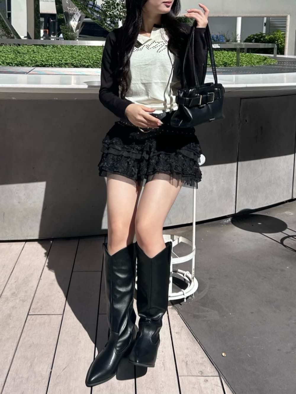 ブラック系のブーツ、ブラック系のスカート、ホワイト系のTシャツ/カットソーを着用したレディースの秋コーディネートの2枚目の写真