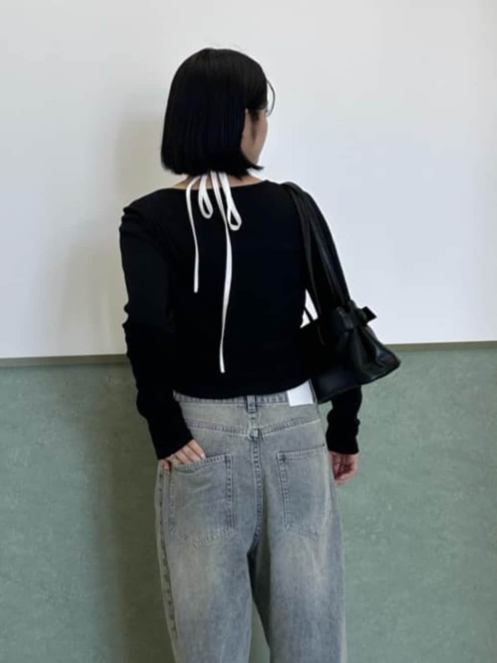 ブルー系のデニムパンツ、ブラック系のショルダーバッグ、ブラック系のカーディガン/ボレロを着用したレディースの秋コーディネートの2枚目の写真