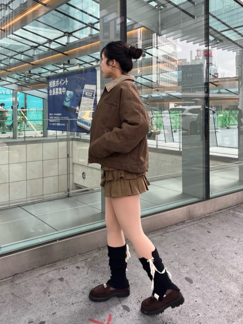 ブラウン系のブルゾン、ブラウン系のスカート、ブラック系のレッグウォーマーを着用したレディースの冬コーディネートの2枚目の写真