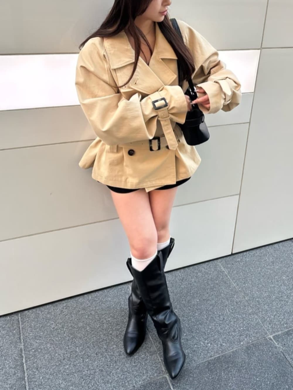 ベージュ系のトレンチコートを着用したレディースの冬コーディネートの2枚目の写真