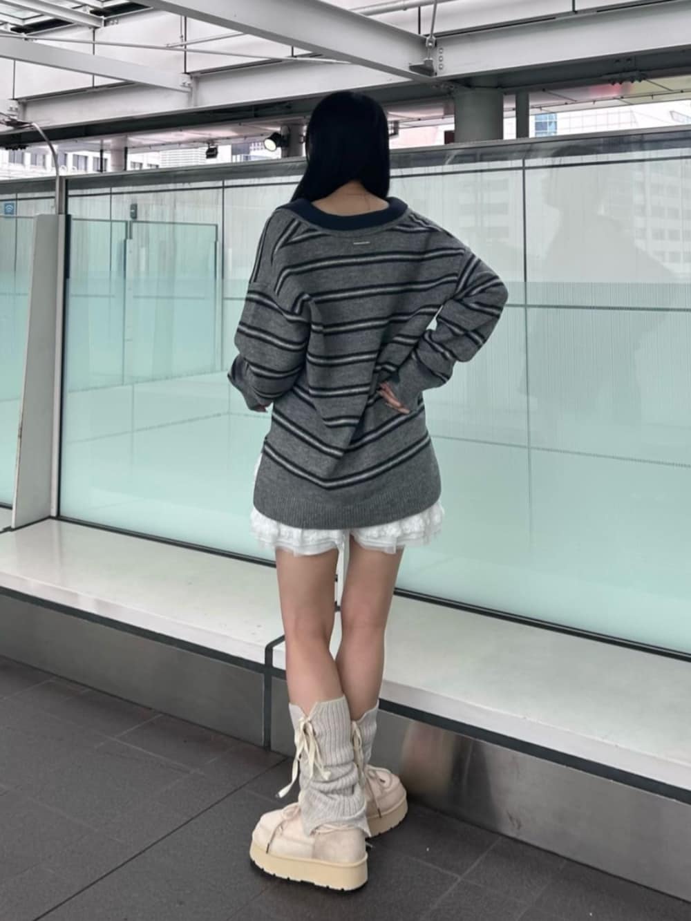 グレー系のニット/セーター、ベージュ系のブーツ、ホワイト系のレッグウォーマーを着用したレディースの秋コーディネートの3枚目の写真