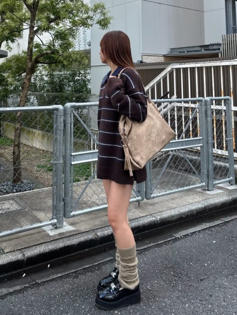 ベージュ系のトートバッグ、ブラウン系のニット/セーター、ベージュ系のレッグウォーマーを着用したレディースの秋コーディネートの2枚目の写真
