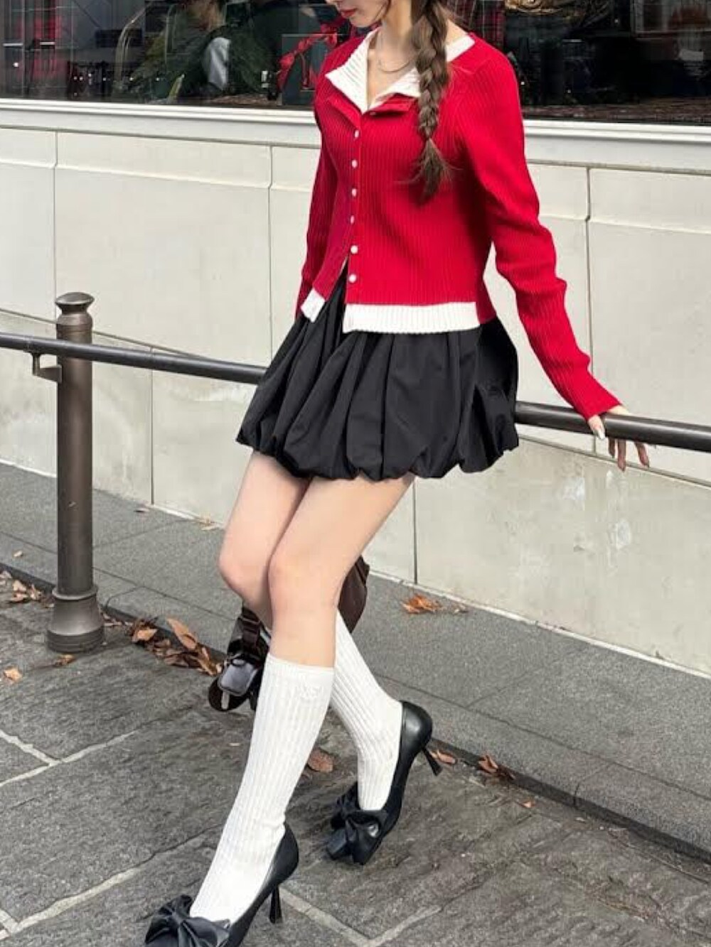 レッド系のニット/セーター、ブラック系のスカート、ブラウン系のショルダーバッグを着用したレディースの冬コーディネートの2枚目の写真