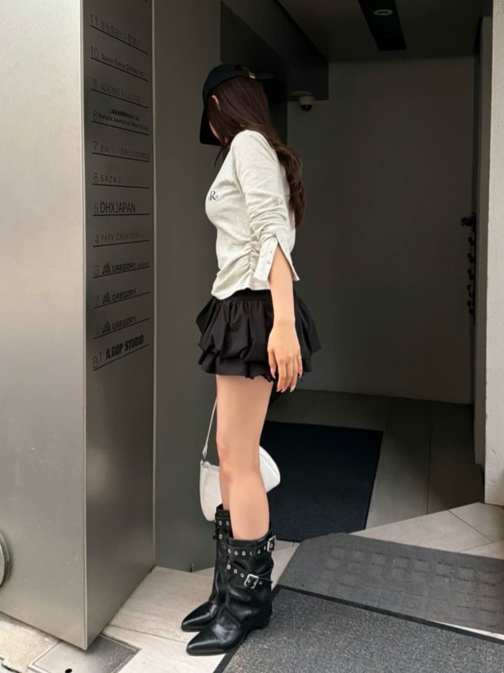 ホワイト系のTシャツ/カットソー、ブラック系のブーツ、ブラック系のスカートを着用したレディースの春コーディネートの2枚目の写真