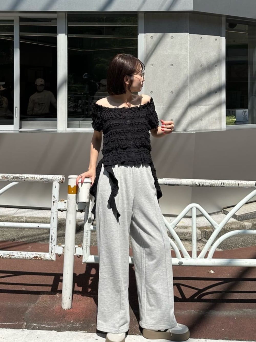 ホワイト系のスニーカー、グレー系のスウェットパンツ、ブラック系のTシャツ/カットソーを着用したレディースの夏コーディネートの2枚目の写真