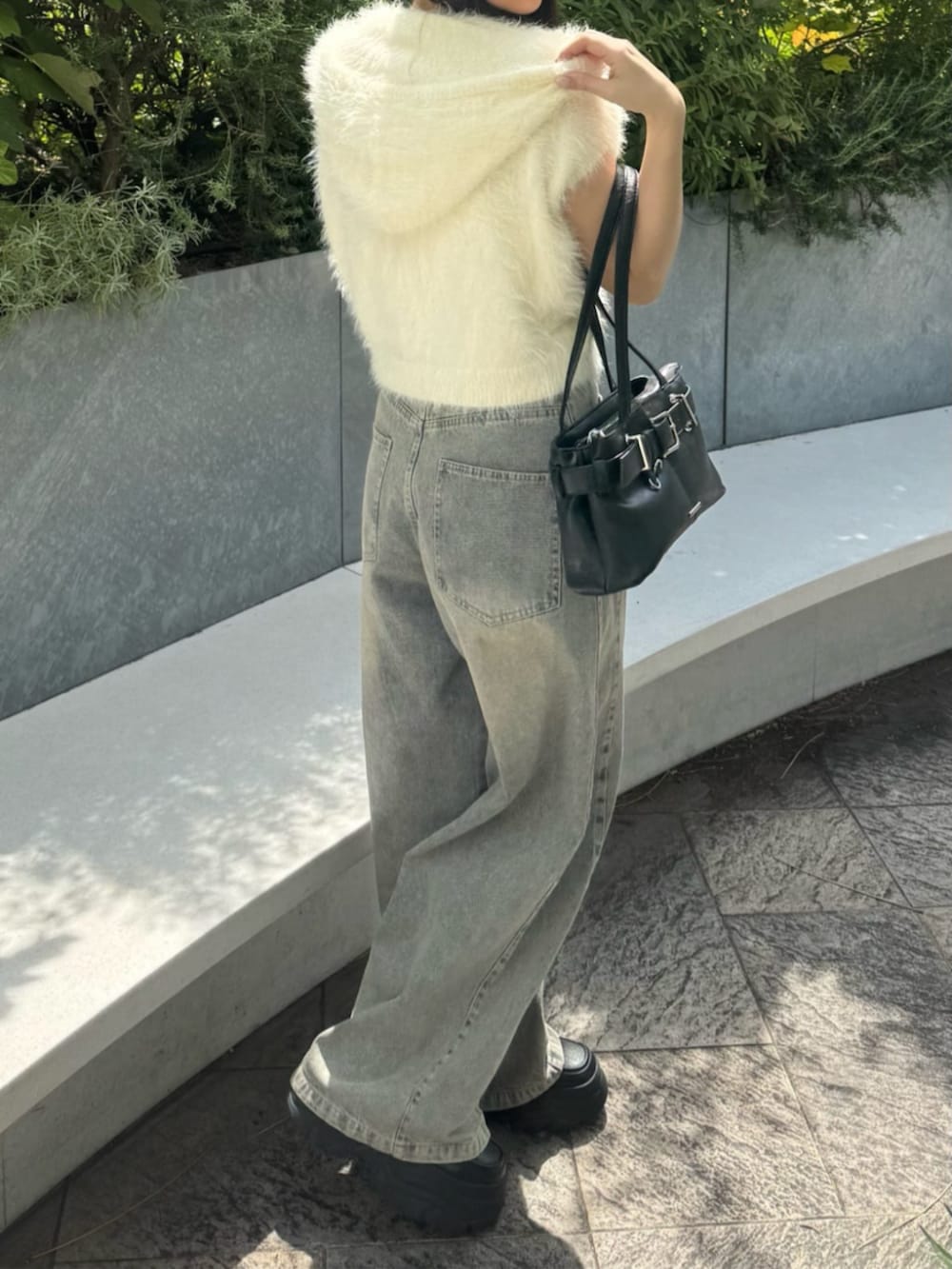 ブルー系のデニムパンツ、ブラック系のショルダーバッグ、ホワイト系のニット/セーターを着用したレディースの秋コーディネートの2枚目の写真