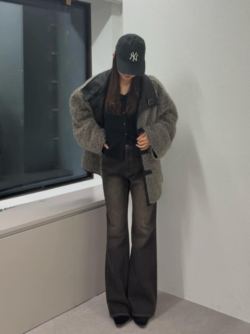 ブラウン系のデニムパンツ、ブラック系のムートンコート、ブラック系のニット/セーターを着用したレディースの秋コーディネートの3枚目の写真
