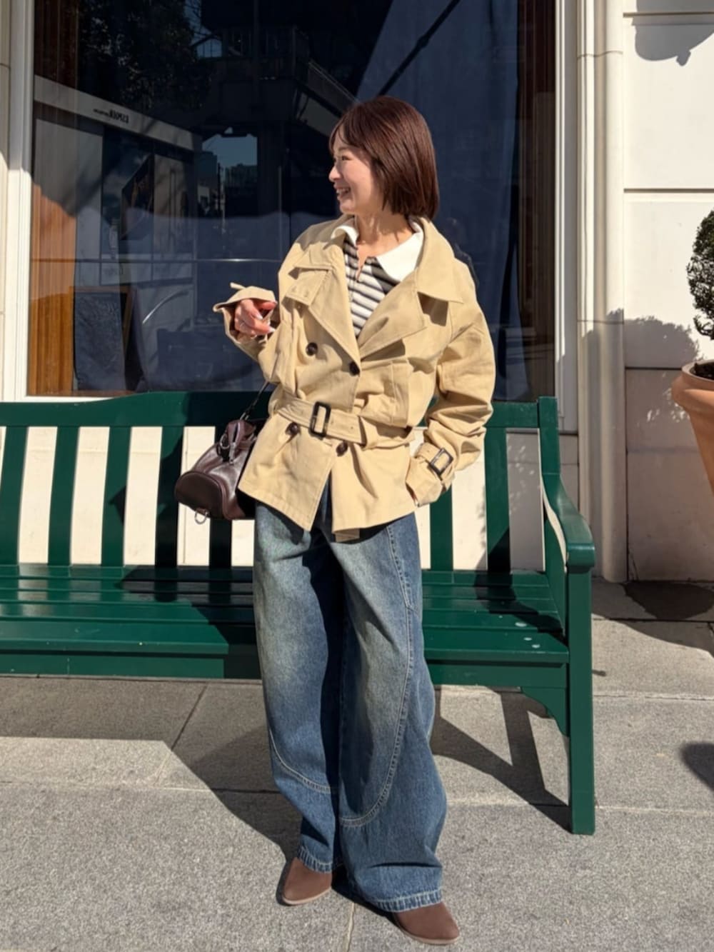 ベージュ系のトレンチコートを着用したレディースの冬コーディネートの2枚目の写真