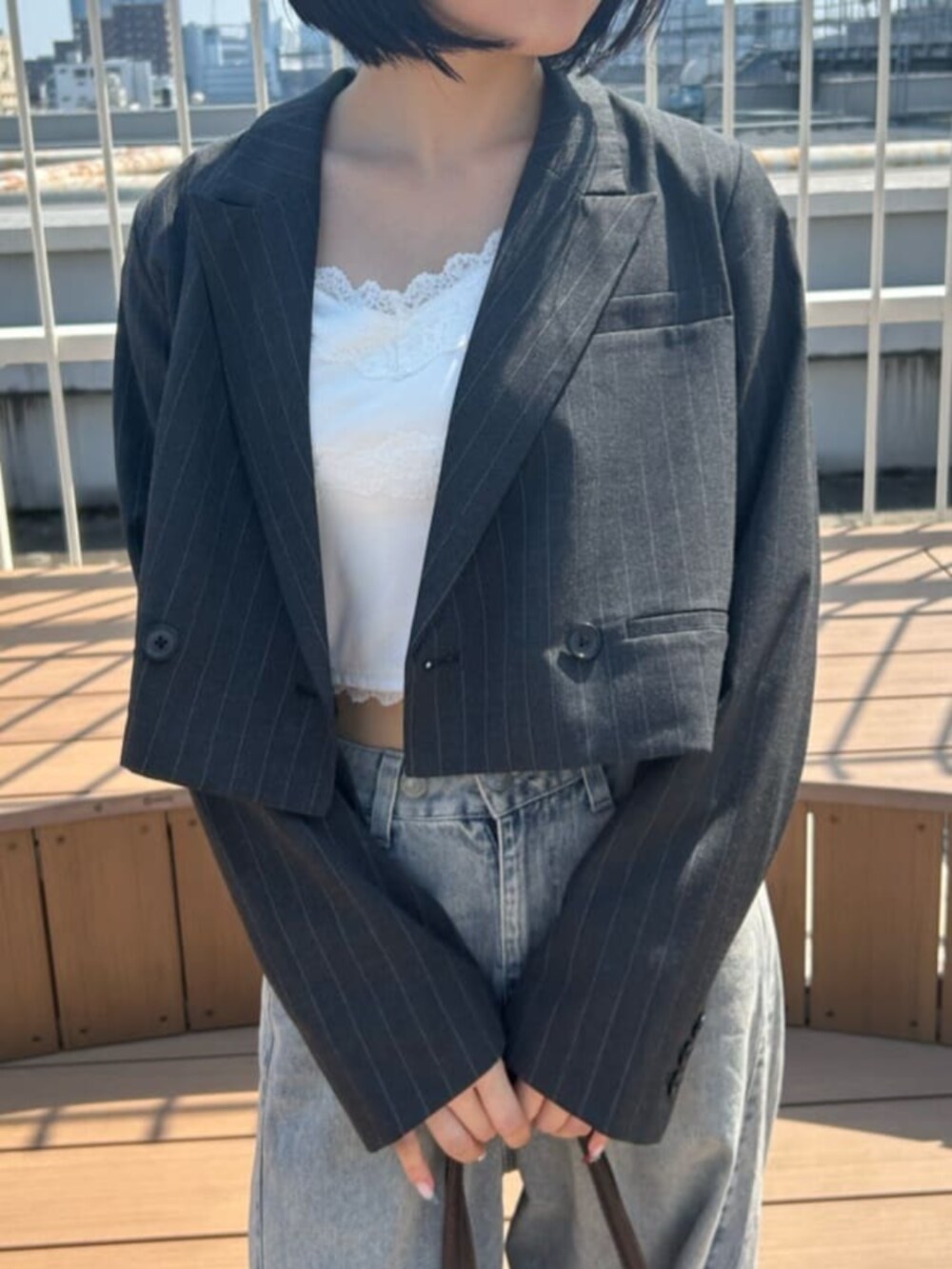 ブルー系のデニムパンツ、ホワイト系のキャミソール、グレー系のその他アウターを着用したレディースの秋コーディネートの3枚目の写真