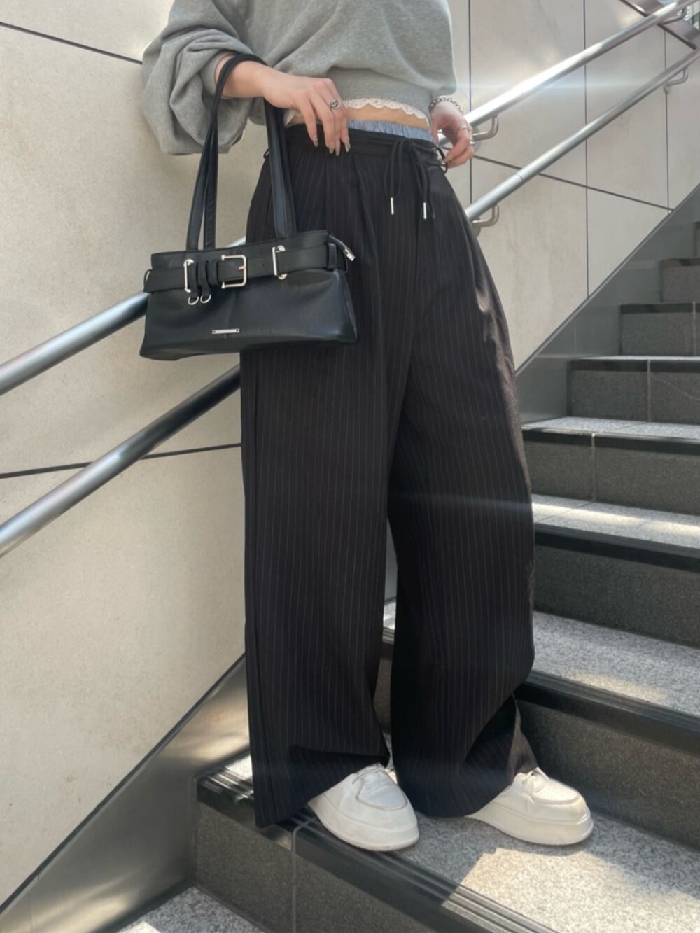 ブラック系のスラックス、ブラック系のショルダーバッグ、グレー系のスウェットを着用したレディースの秋コーディネートの3枚目の写真