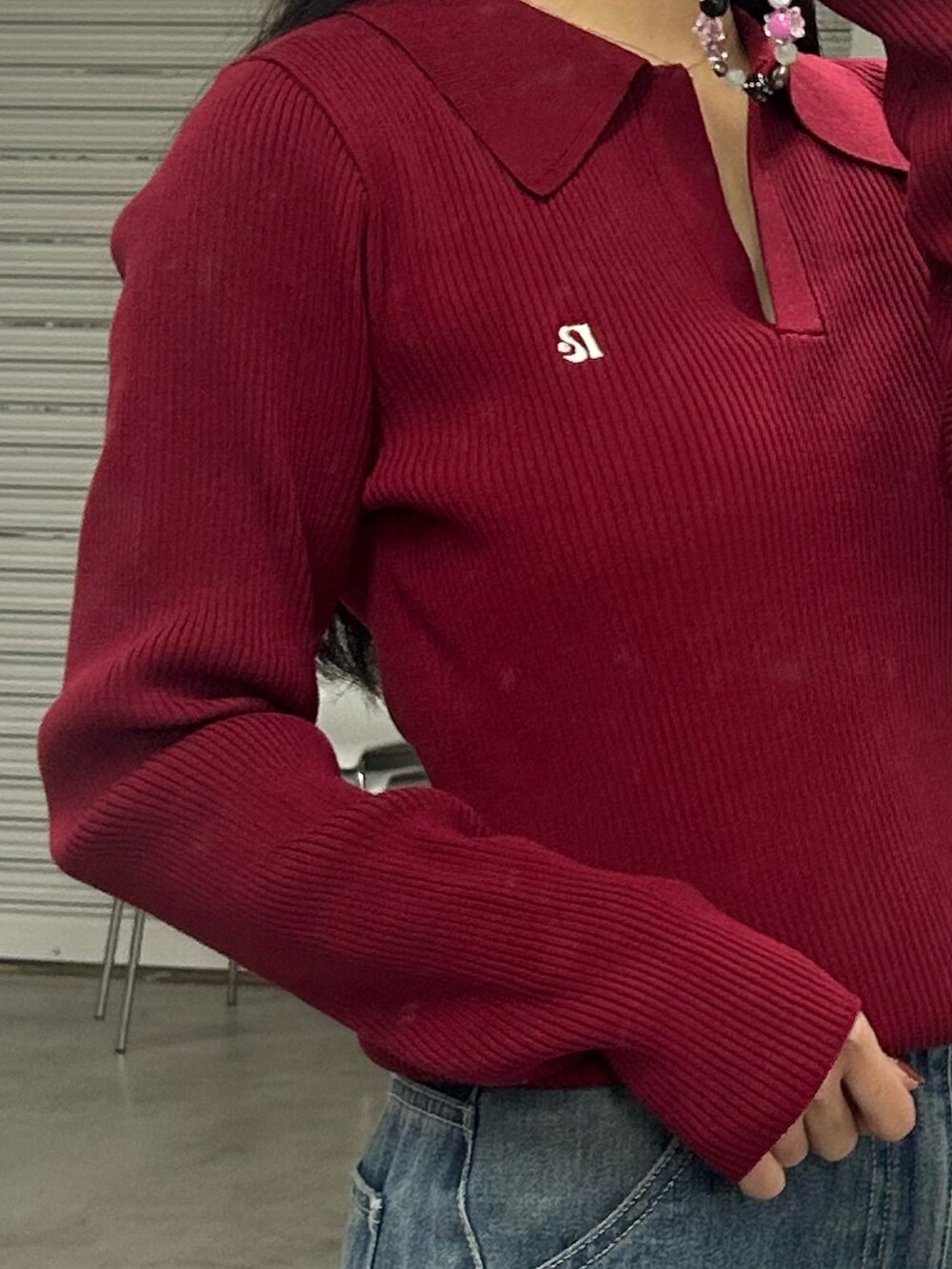 レッド系のニット/セーター、ブルー系のデニムパンツを着用したレディースの冬コーディネートの2枚目の写真