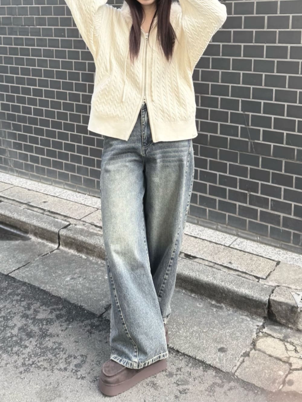 ベージュ系のパーカー、ブルー系のデニムパンツ、ブラウン系のブーツを着用したレディースの秋コーディネートの2枚目の写真