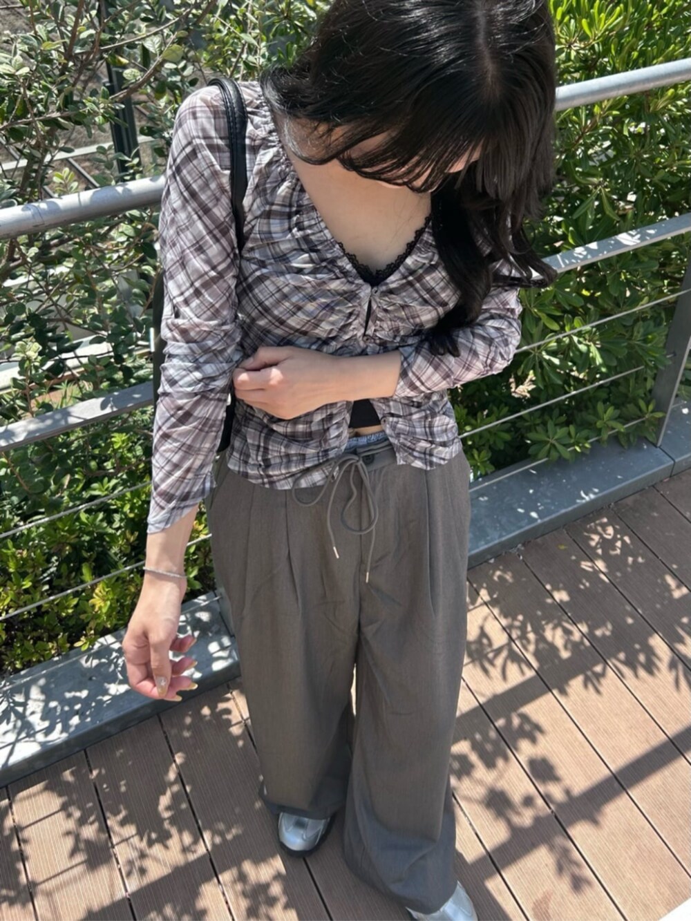 グレー系のスラックス、ブラック系のショルダーバッグ、ブラック系のシャツ/ブラウスを着用したレディースの秋コーディネートの2枚目の写真