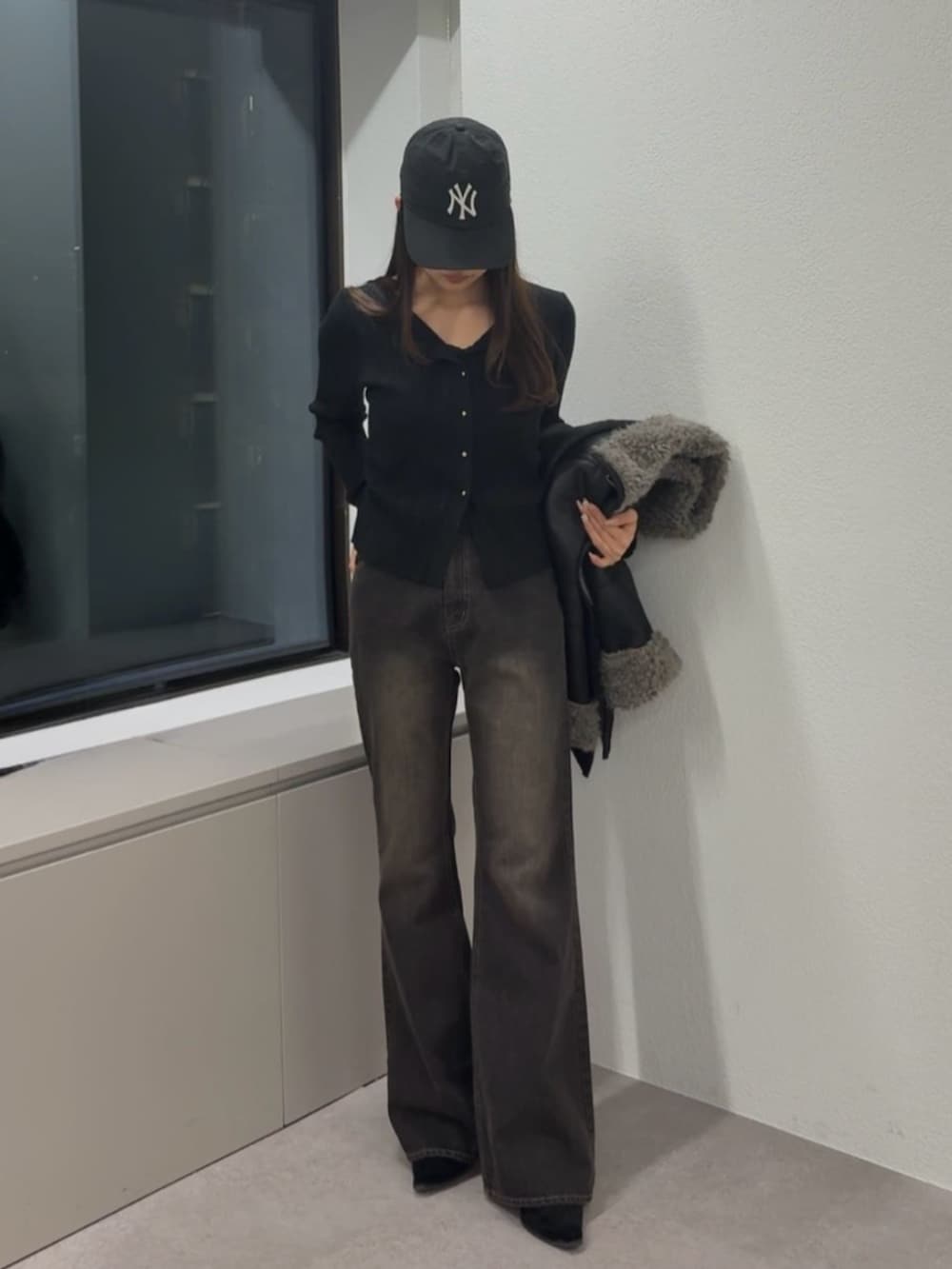 ブラウン系のデニムパンツ、ブラック系のムートンコート、ブラック系のニット/セーターを着用したレディースの秋コーディネートの2枚目の写真