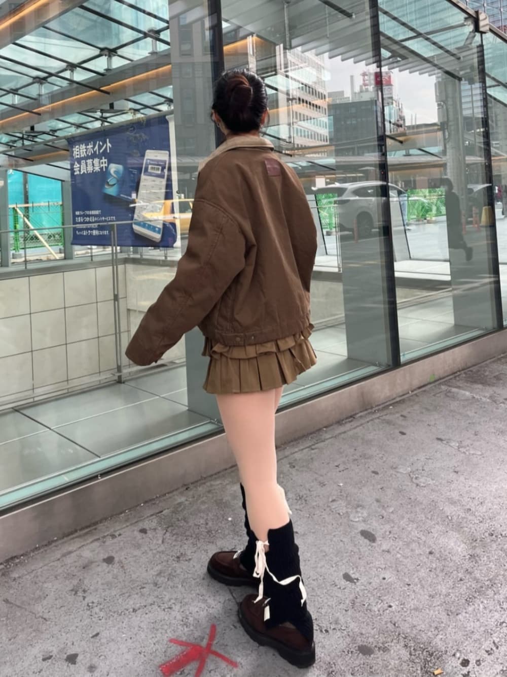 ブラウン系のブルゾン、ブラウン系のスカート、ブラック系のレッグウォーマーを着用したレディースの冬コーディネートの3枚目の写真