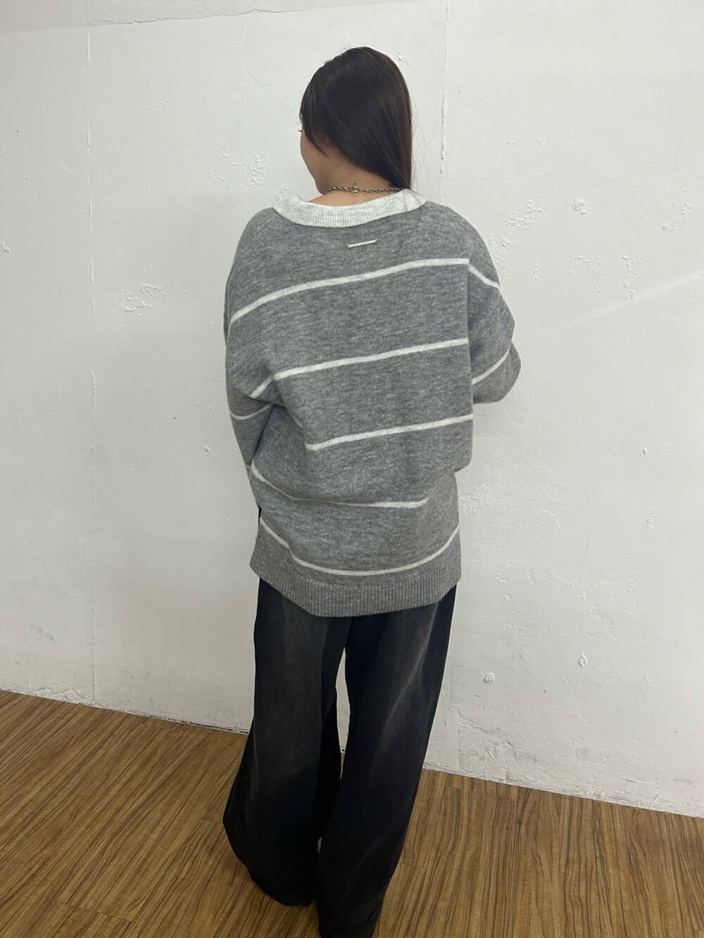 グレー系のニット/セーター、ブラック系のデニムパンツを着用したレディースの秋コーディネートの2枚目の写真