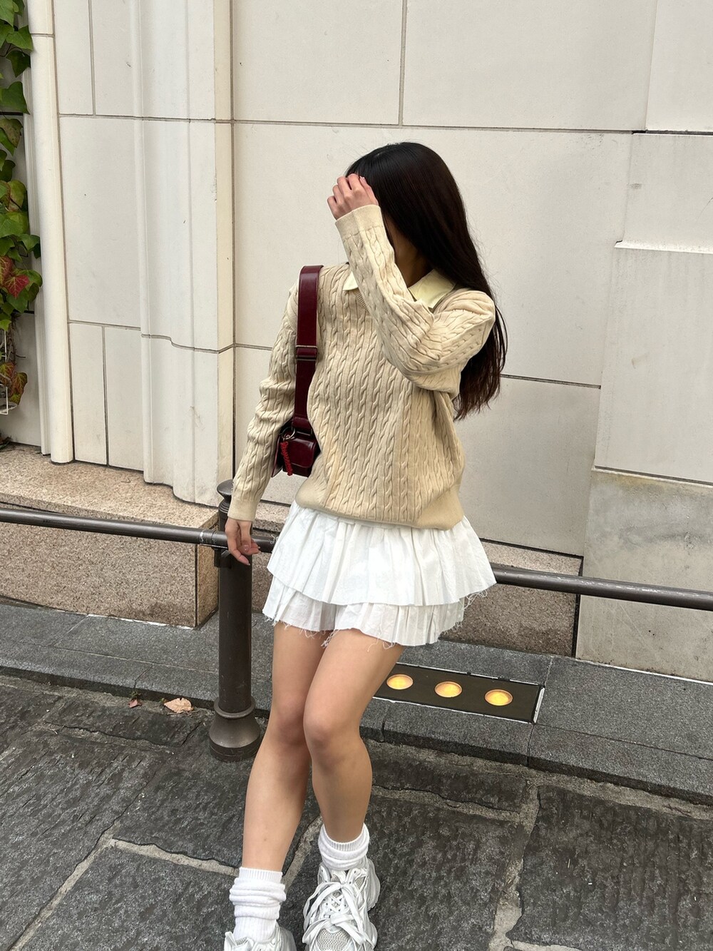 ベージュ系のニット/セーター、ホワイト系のスカート、シルバー系のスニーカーを着用したレディースの冬コーディネートの2枚目の写真