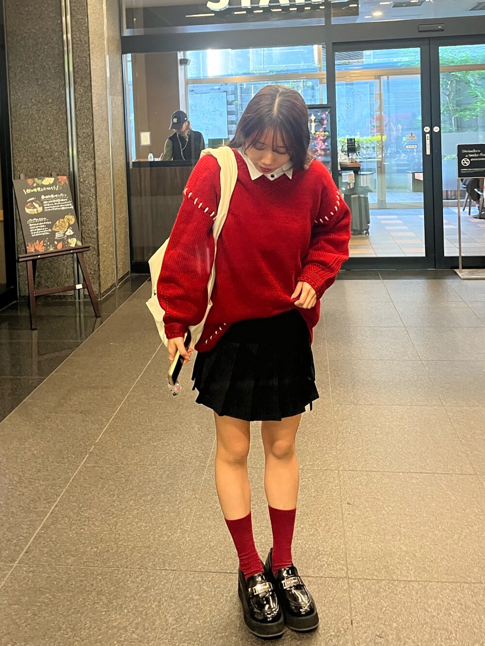 レッド系のニット/セーター、ブラック系のスカート、ブラック系のその他シューズを着用したレディースの秋コーディネートの2枚目の写真