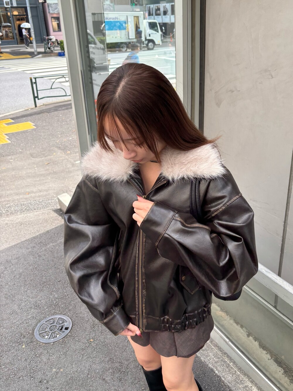 ブラック系のブルゾン、ホワイト系のTシャツ/カットソー、ブラウン系のスカートを着用したレディースの秋コーディネートの3枚目の写真