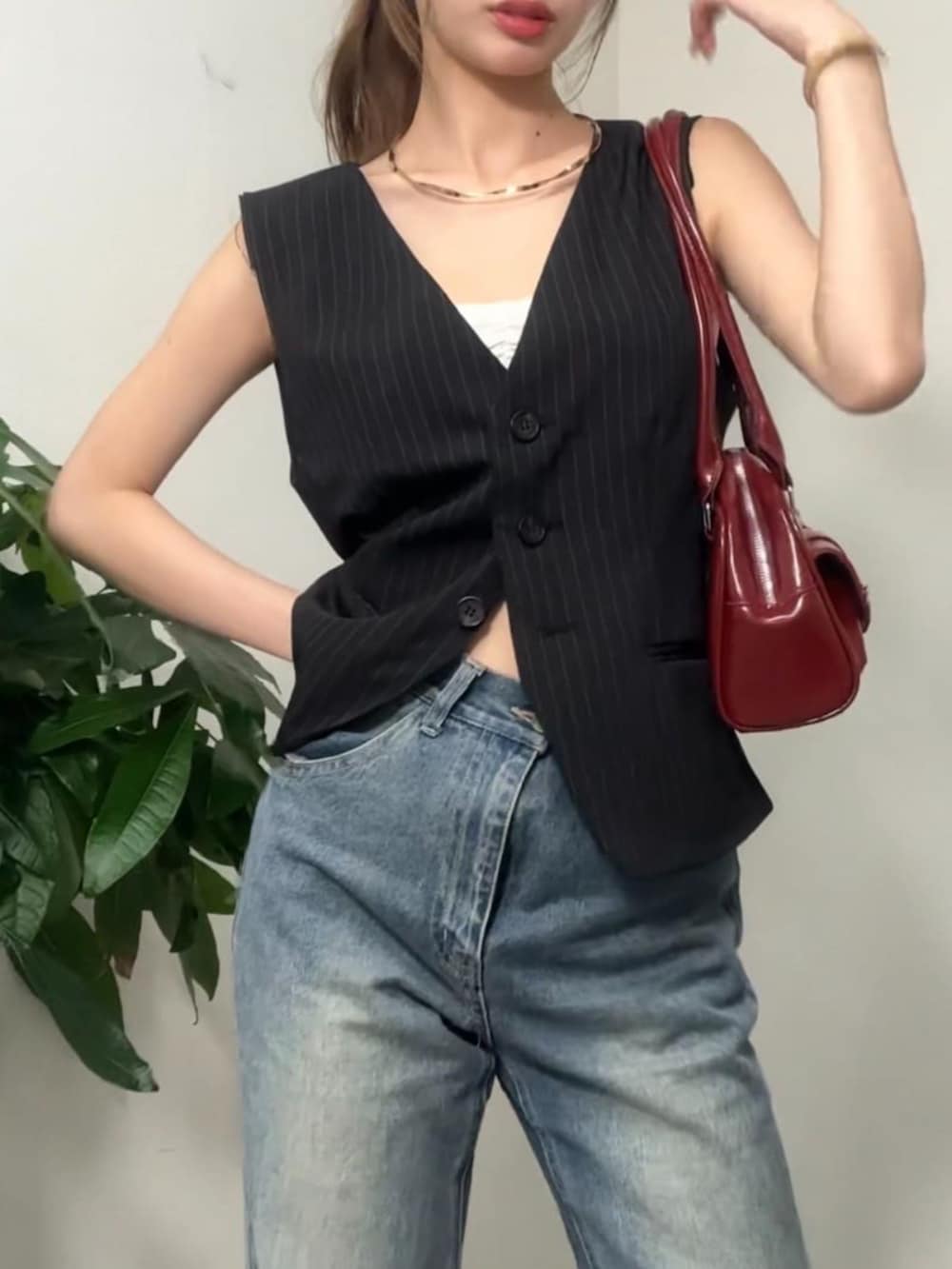 ブルー系のデニムパンツ、ブラック系のベストを着用したレディースの夏コーディネートの3枚目の写真