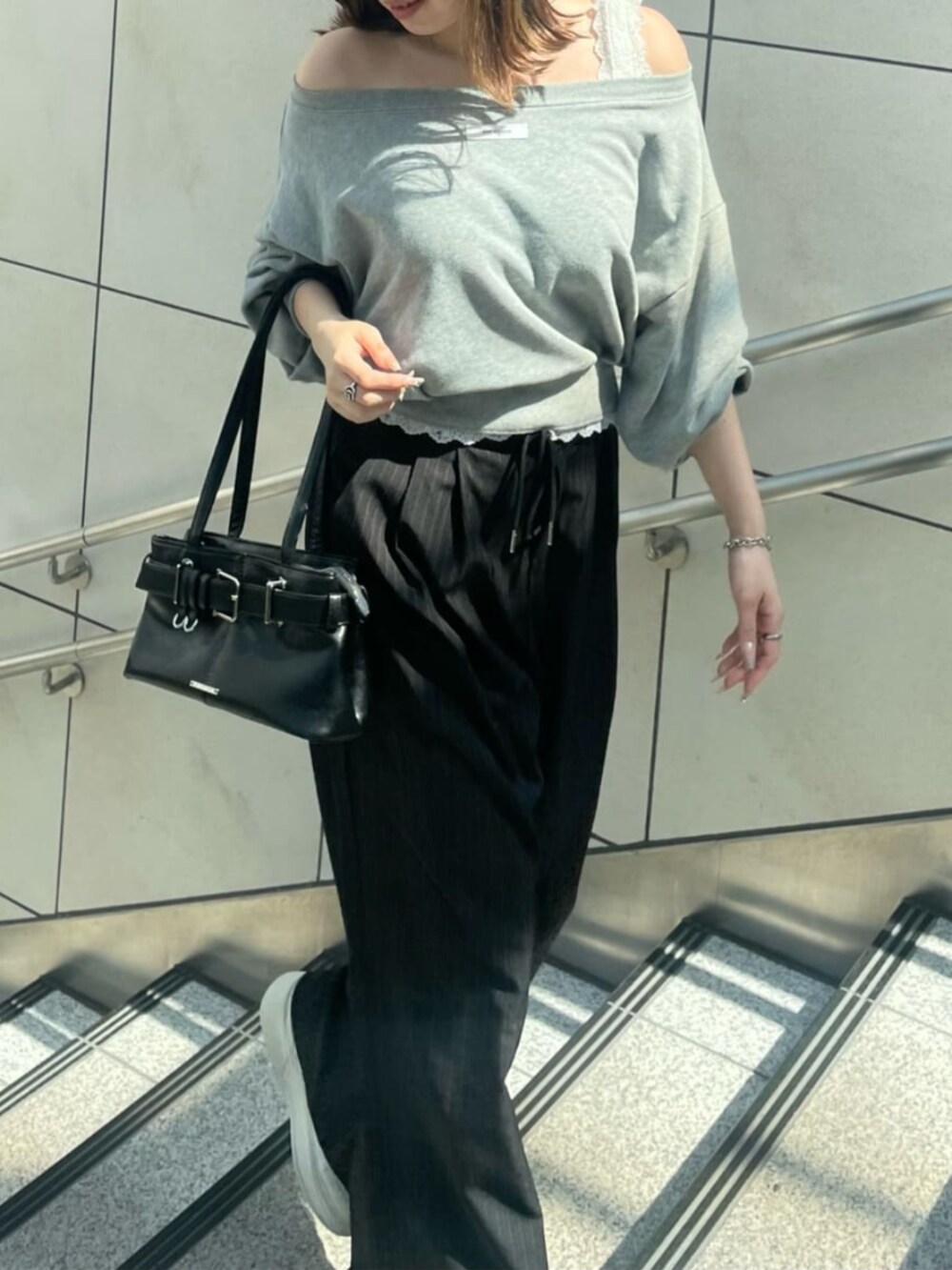 ブラック系のスラックス、ブラック系のショルダーバッグ、グレー系のスウェットを着用したレディースの秋コーディネートの2枚目の写真