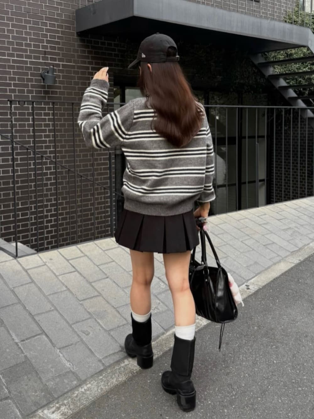 グレー系のニット/セーター、ブラック系のスカートを着用したレディースの秋コーディネートの3枚目の写真