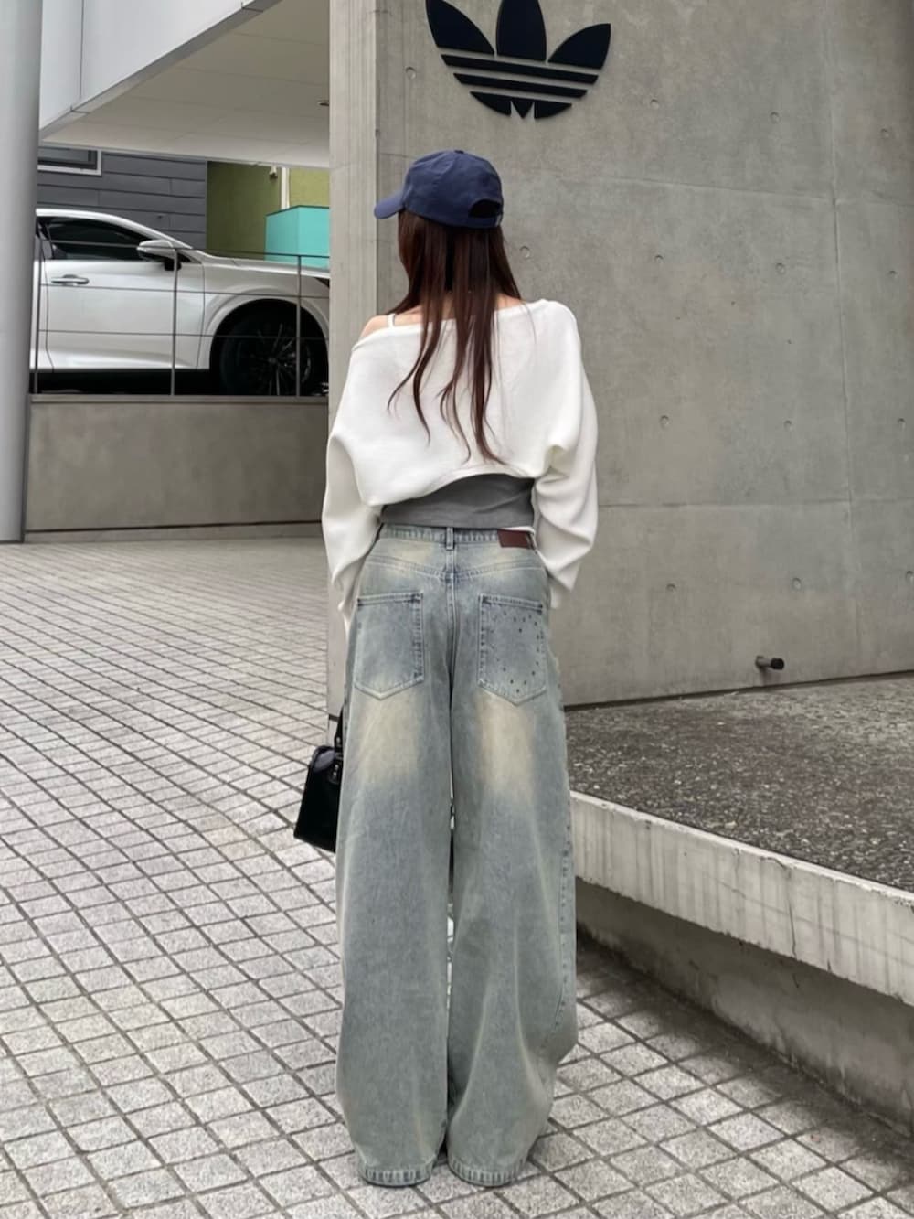 ブルー系のデニムパンツ、ブラック系のショルダーバッグ、ホワイト系のニット/セーターを着用したレディースの春コーディネートの2枚目の写真