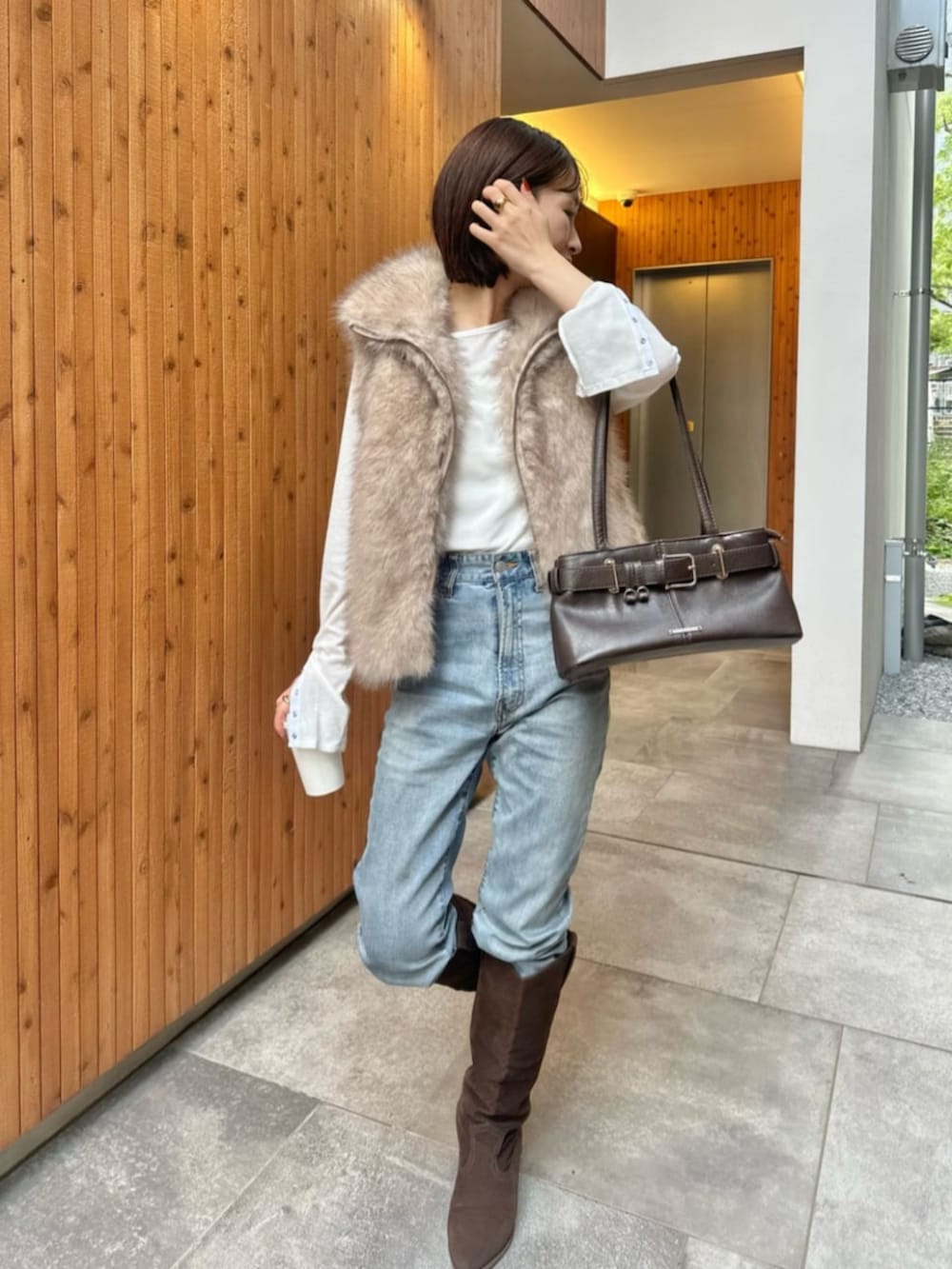 ホワイト系のベスト、ホワイト系のTシャツ/カットソー、ブラウン系のブーツを着用したレディースの秋コーディネートの2枚目の写真