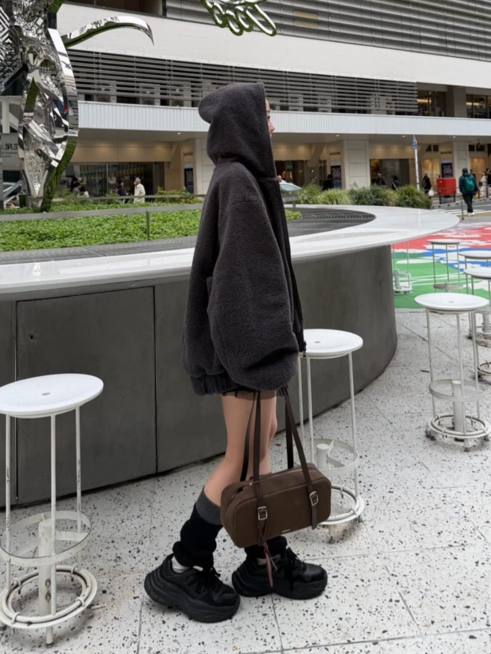 ブラック系のスカート、グレー系のブルゾン、ホワイト系のTシャツ/カットソーを着用したレディースの秋コーディネートの2枚目の写真