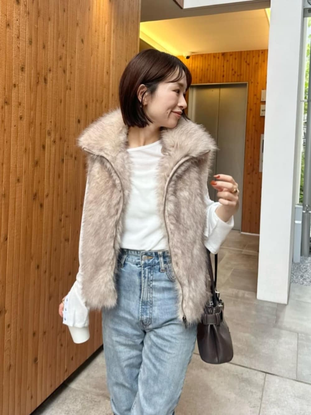 ホワイト系のベスト、ホワイト系のTシャツ/カットソー、ブラウン系のブーツを着用したレディースの秋コーディネートの3枚目の写真