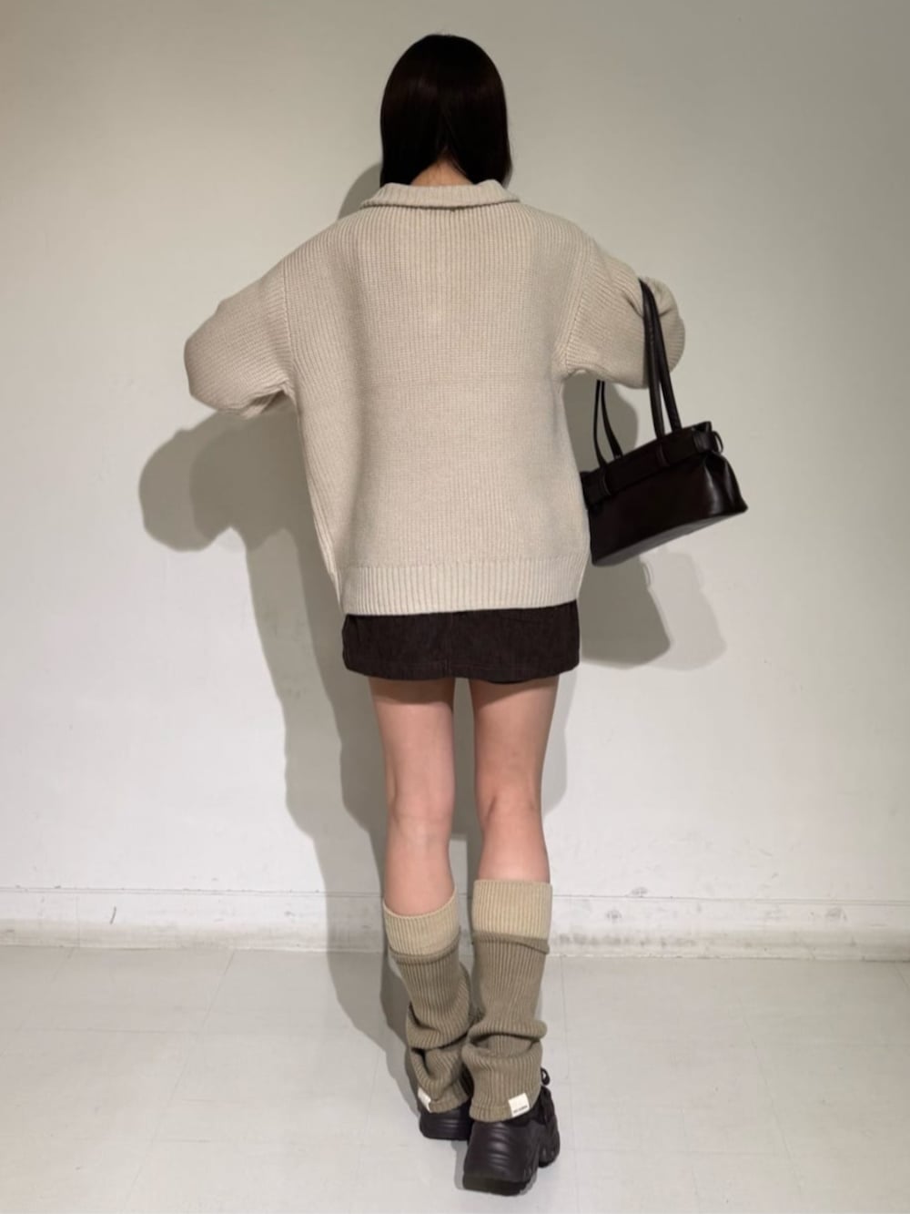 ブラウン系のスカート、ベージュ系のニット/セーター、ブラウン系のローファーを着用したレディースの秋コーディネートの2枚目の写真