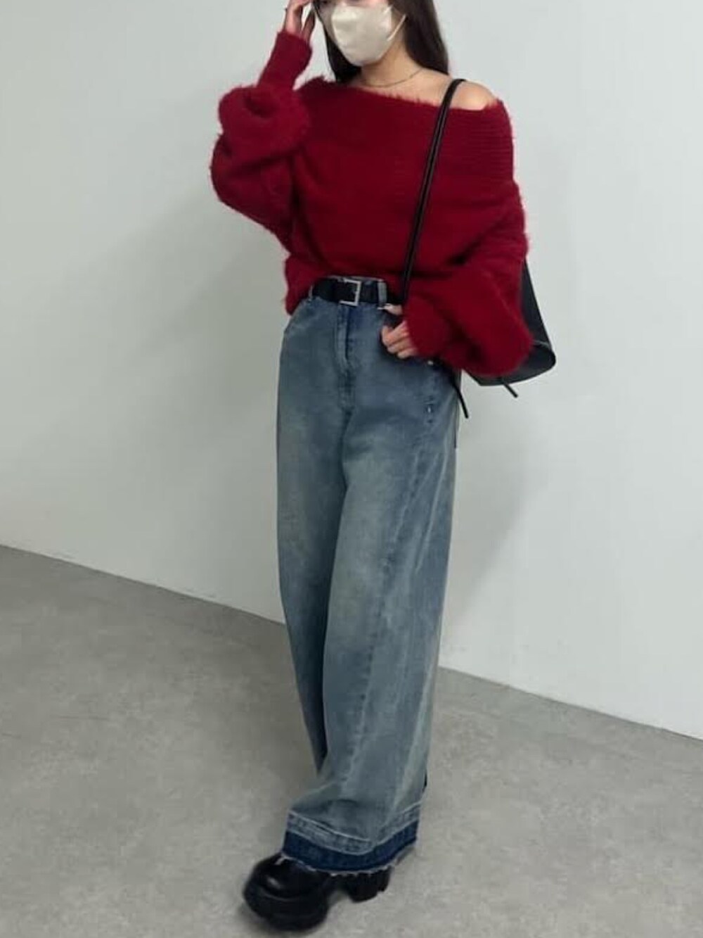 グレー系のニット/セーター、ブルー系のデニムパンツ、ブラック系のバックパック/リュックを着用したレディースの冬コーディネートの2枚目の写真