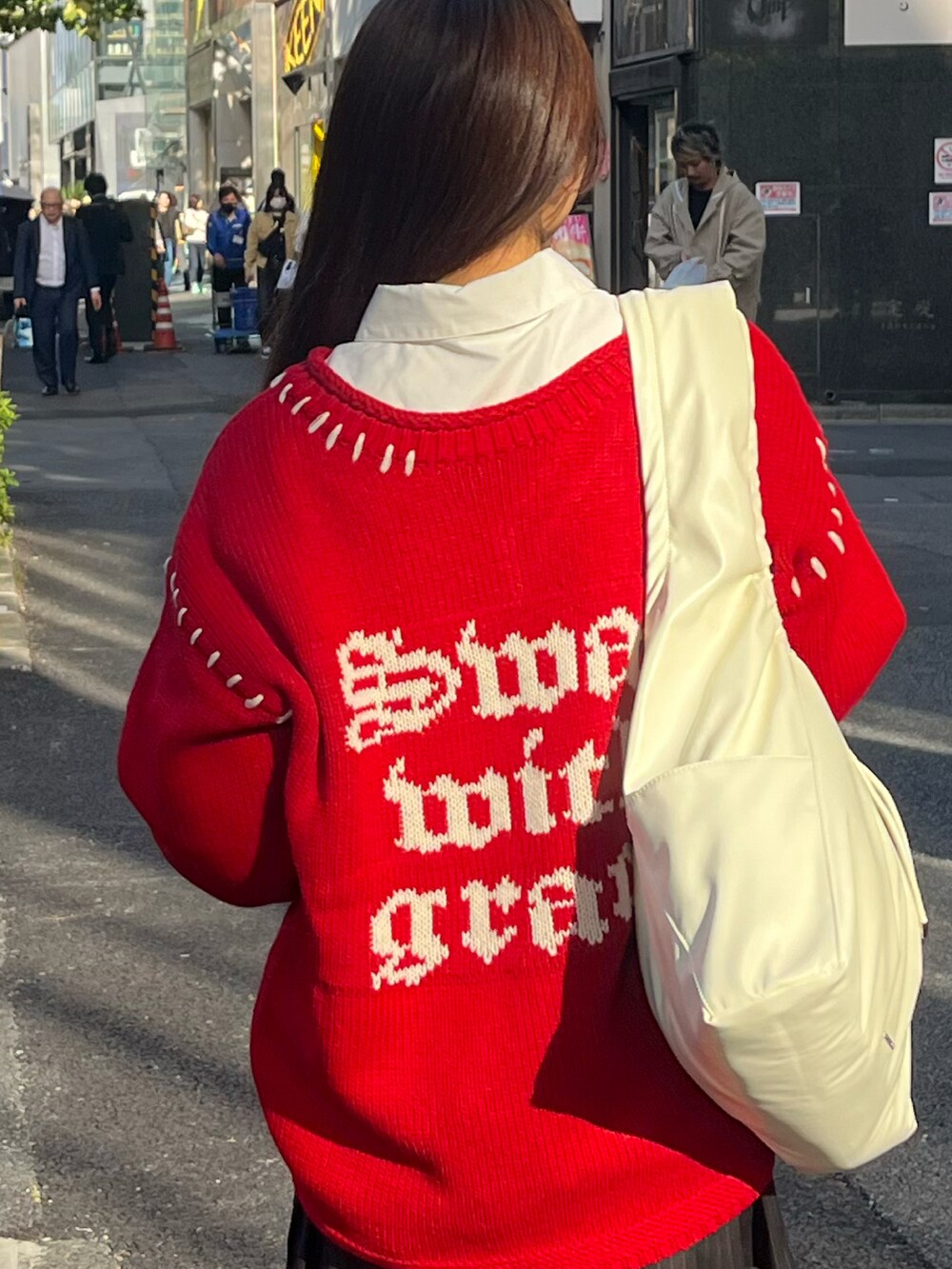 レッド系のニット/セーター、ブラック系のスカート、ブラック系のその他シューズを着用したレディースの秋コーディネートの3枚目の写真