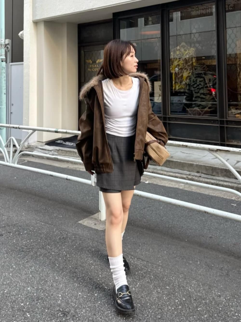 ベージュ系のブルゾン、ブラック系のスカート、イエロー系のトートバッグを着用したレディースの秋コーディネートの2枚目の写真