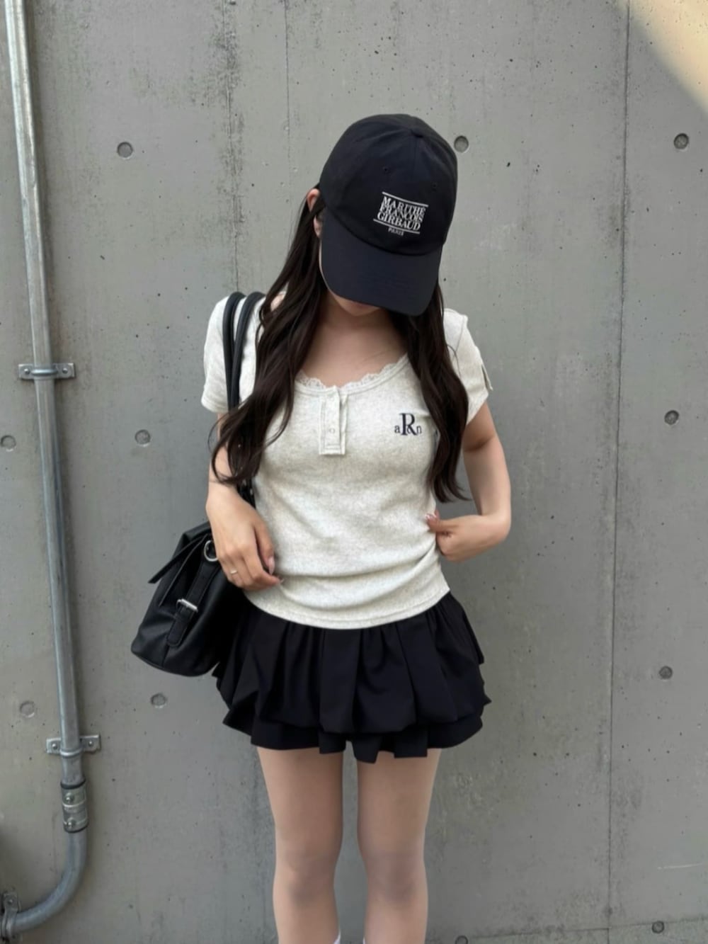 ブラック系のスカート、ホワイト系のTシャツ/カットソーを着用したレディースの春コーディネートの2枚目の写真