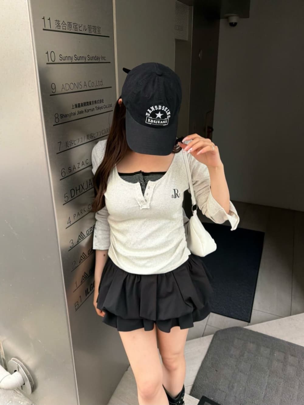 ホワイト系のTシャツ/カットソー、ブラック系のブーツ、ブラック系のスカートを着用したレディースの春コーディネートの3枚目の写真