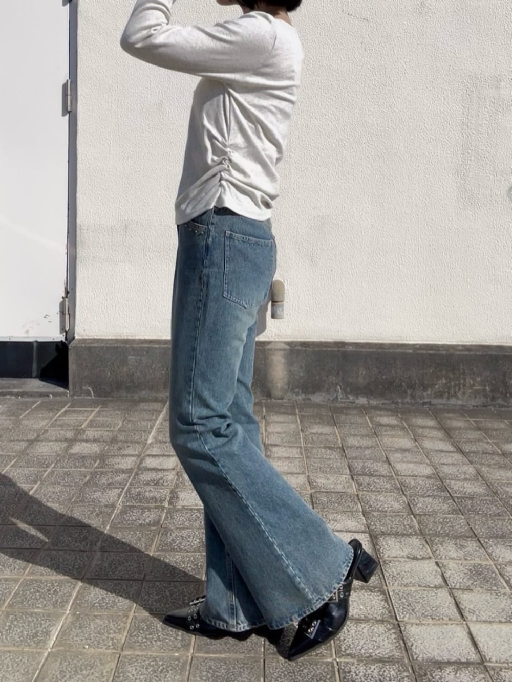 ホワイト系のTシャツ/カットソー、ブラック系のその他シューズ、ブルー系のデニムパンツを着用したレディースの冬コーディネートの2枚目の写真