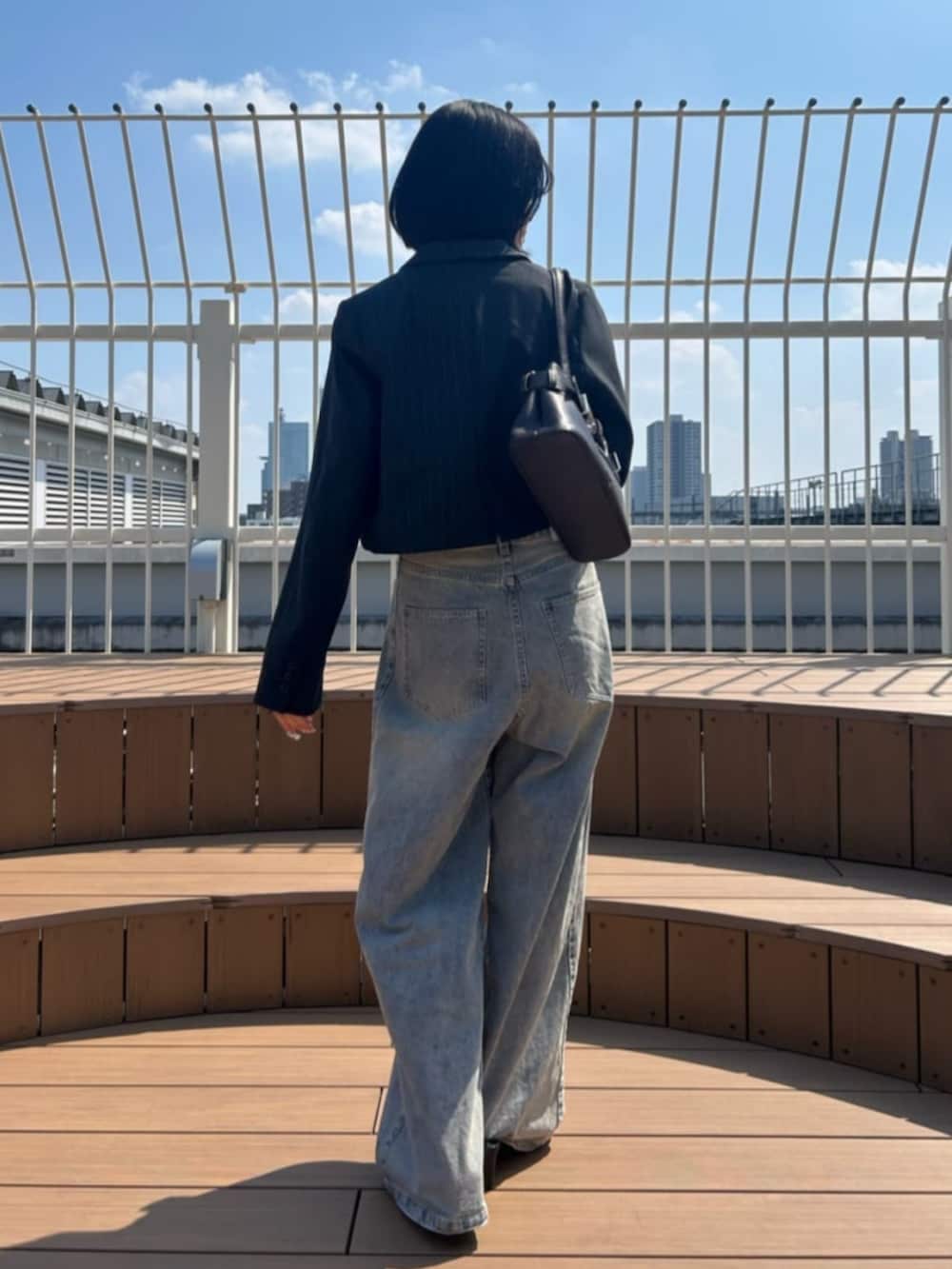 ブルー系のデニムパンツ、ホワイト系のキャミソール、グレー系のその他アウターを着用したレディースの秋コーディネートの2枚目の写真