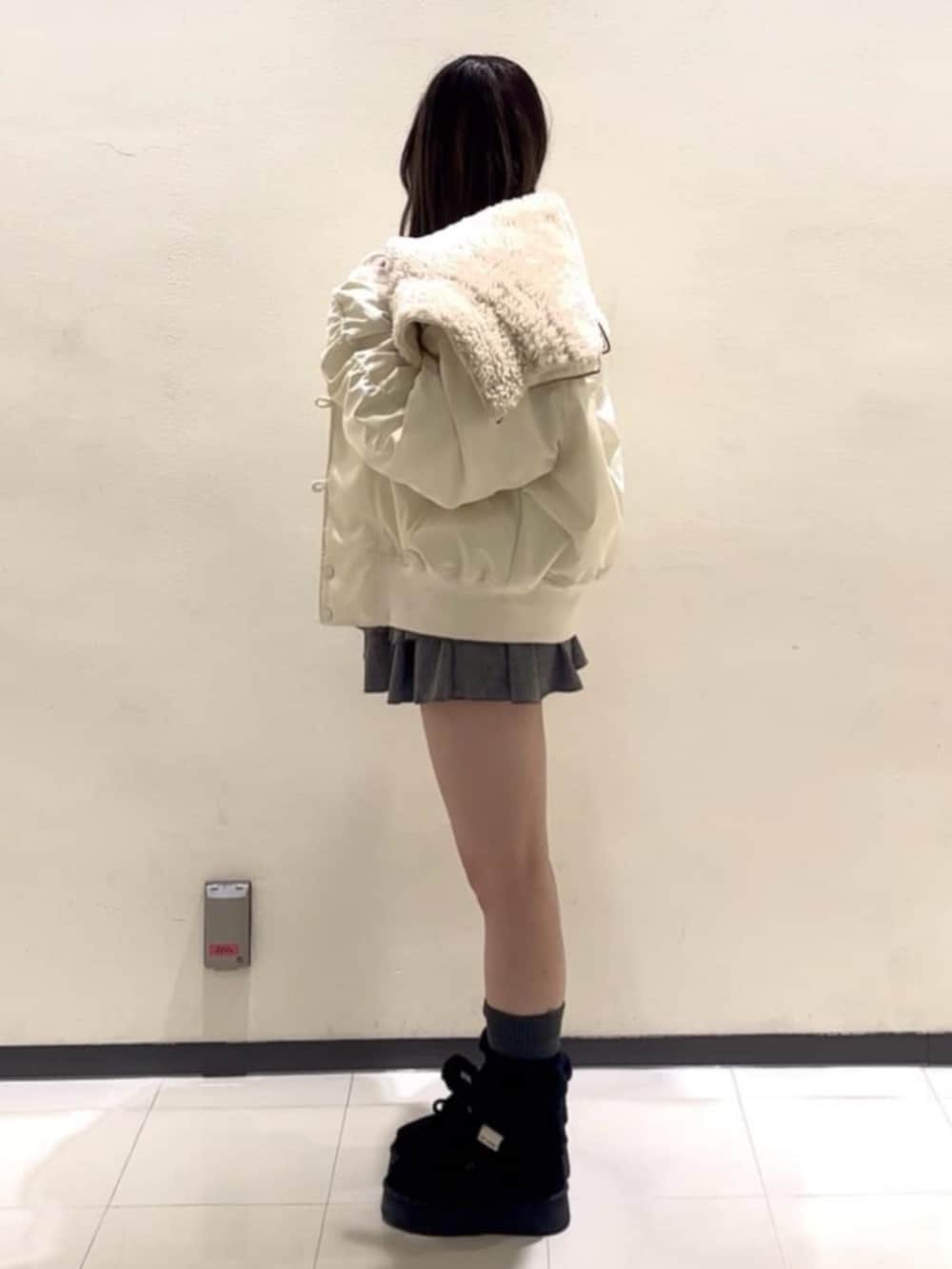 ホワイト系のブルゾン、グレー系のニット/セーター、グレー系のスカートを着用したレディースの冬コーディネートの2枚目の写真