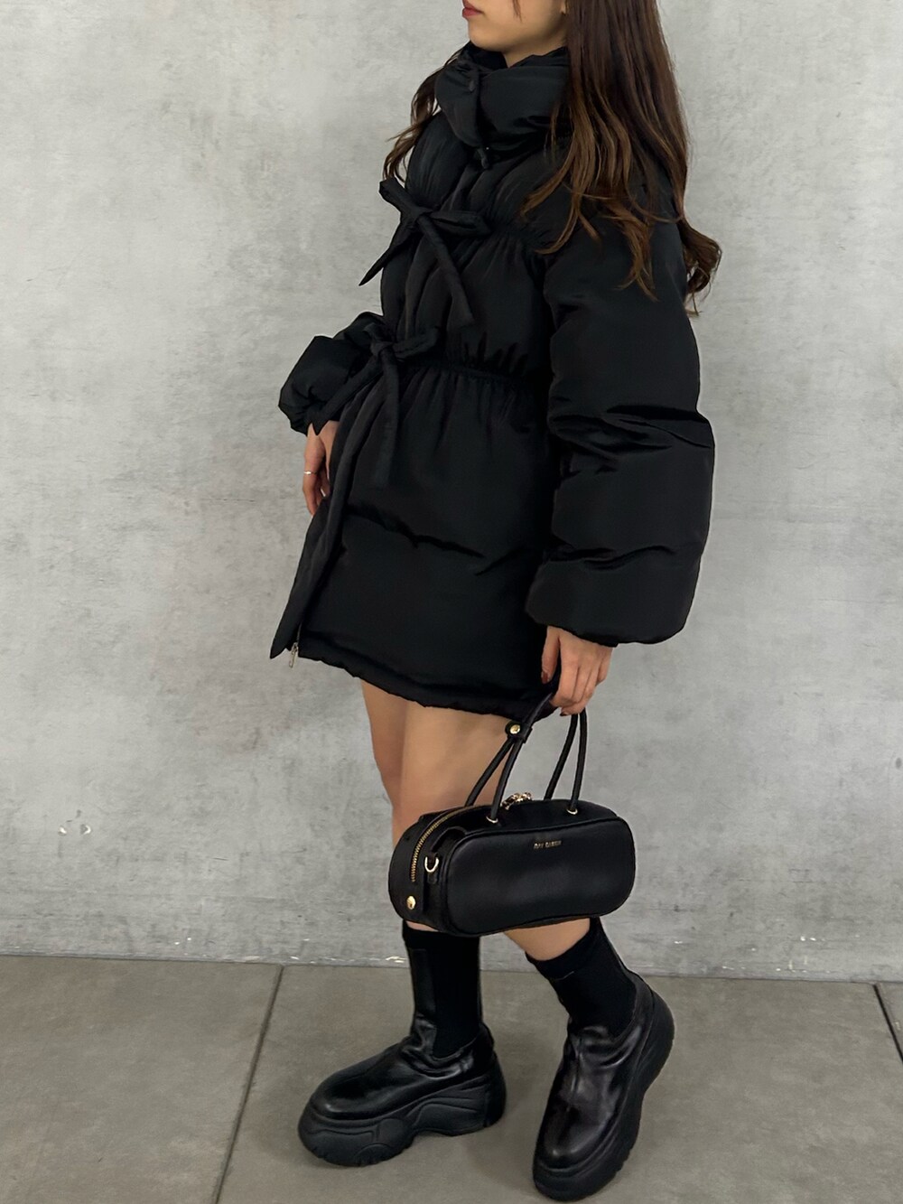 ブラック系のダウンジャケット/コート、レッド系のボストンバッグ、ブラック系のブーツを着用したレディースの冬コーディネートの2枚目の写真