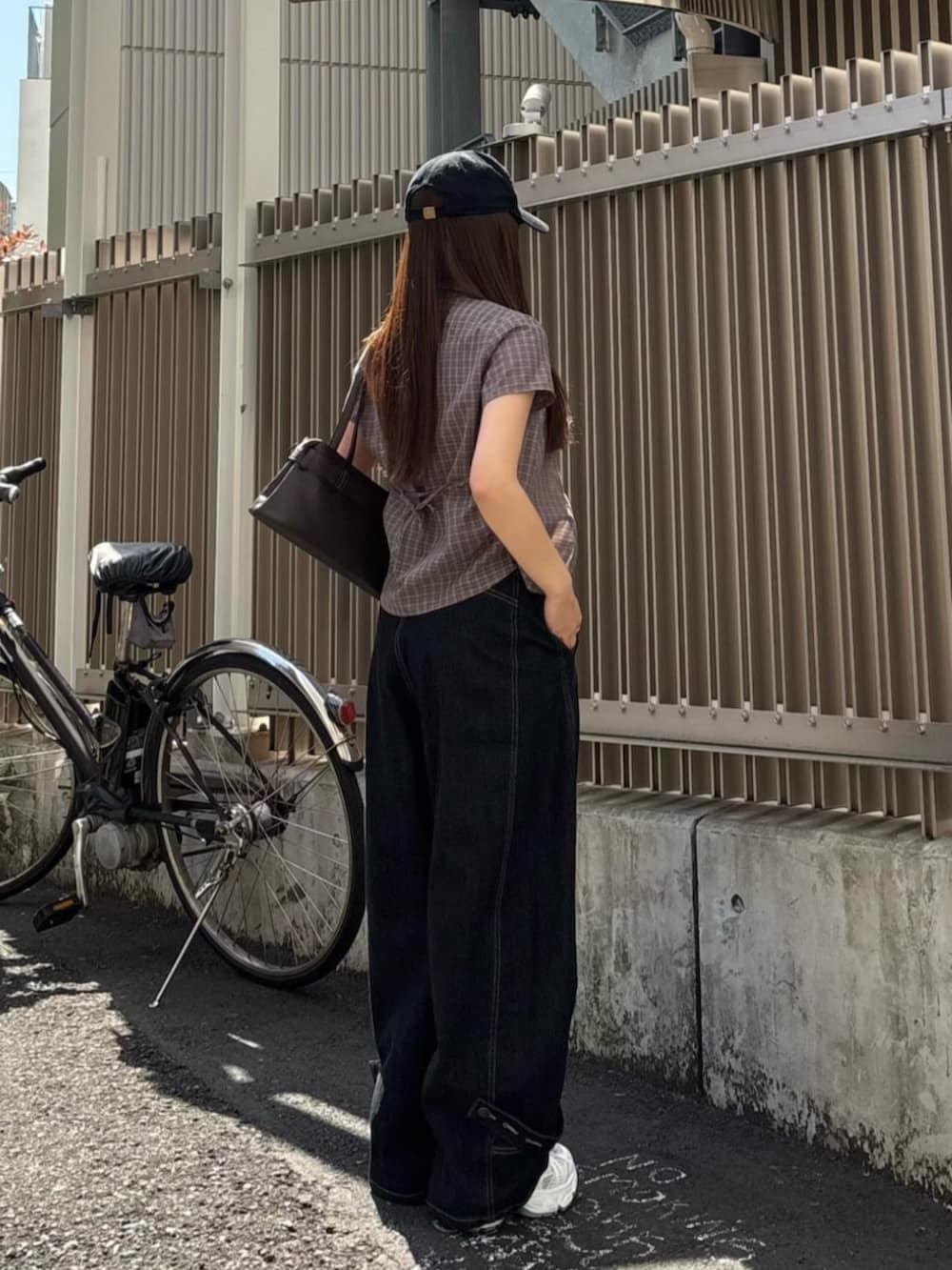 ブラック系のデニムパンツ、ホワイト系のスニーカー、ブラウン系のシャツ/ブラウスを着用したレディースの春コーディネートの2枚目の写真