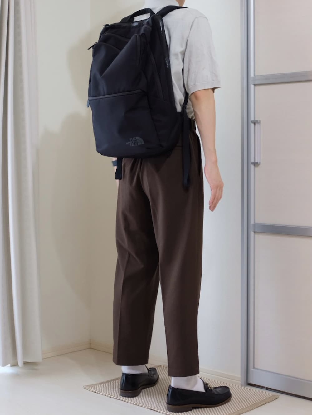 ブラウン系のパンツ、ホワイト系のトップス、ブラック系のバックパック/リュックを着用したメンズの秋コーディネートの3枚目の写真