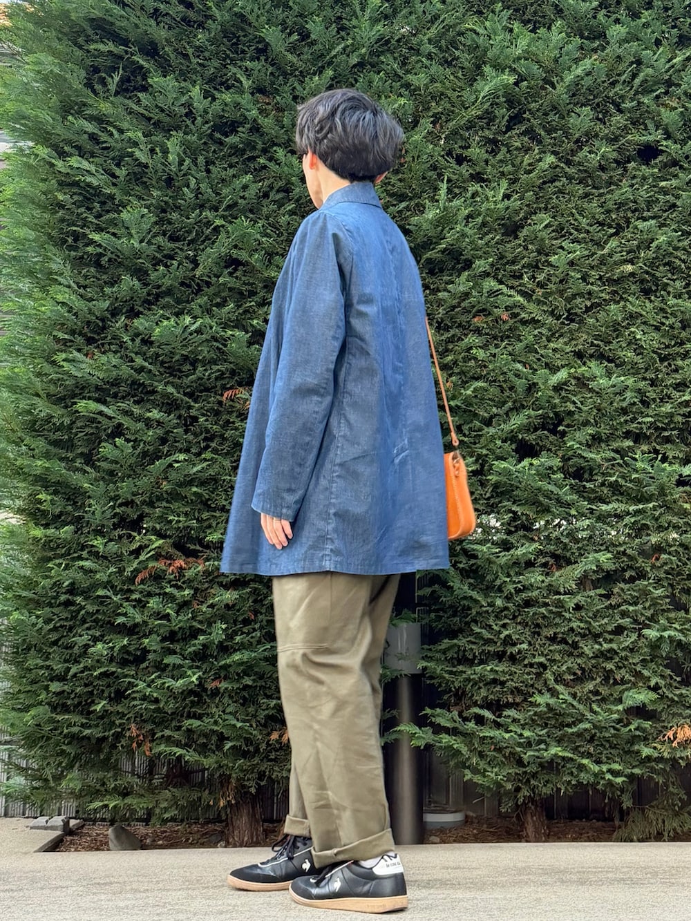 ベージュ系のベスト、ブルー系のその他アウター、オレンジ系のショルダーバッグを着用したメンズの秋コーディネートの4枚目の写真