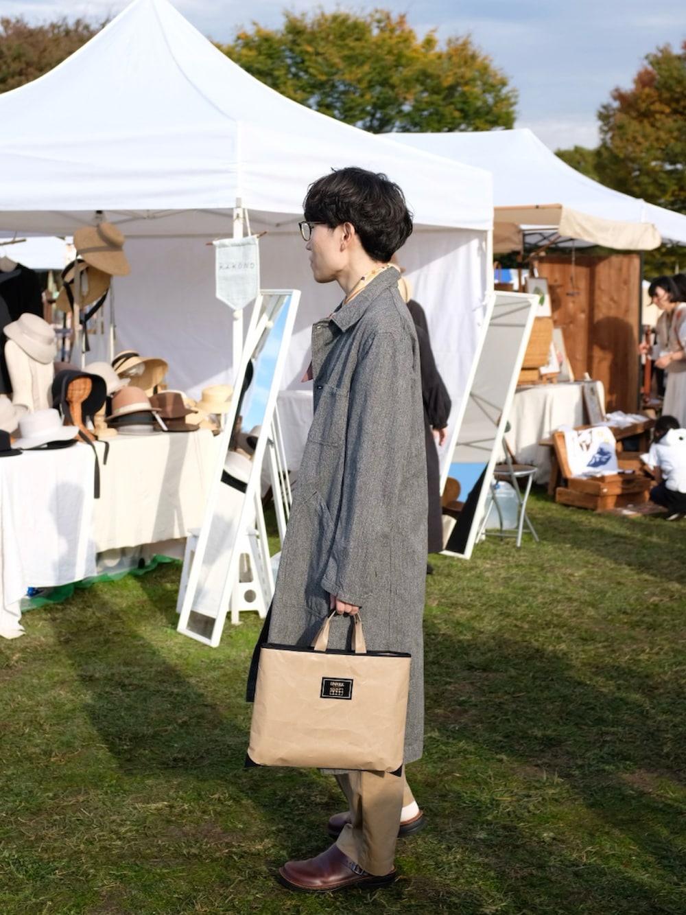 グレー系のその他アウター、ブラック系のTシャツ/カットソー、ベージュ系のパンツを着用したメンズの秋コーディネートの2枚目の写真