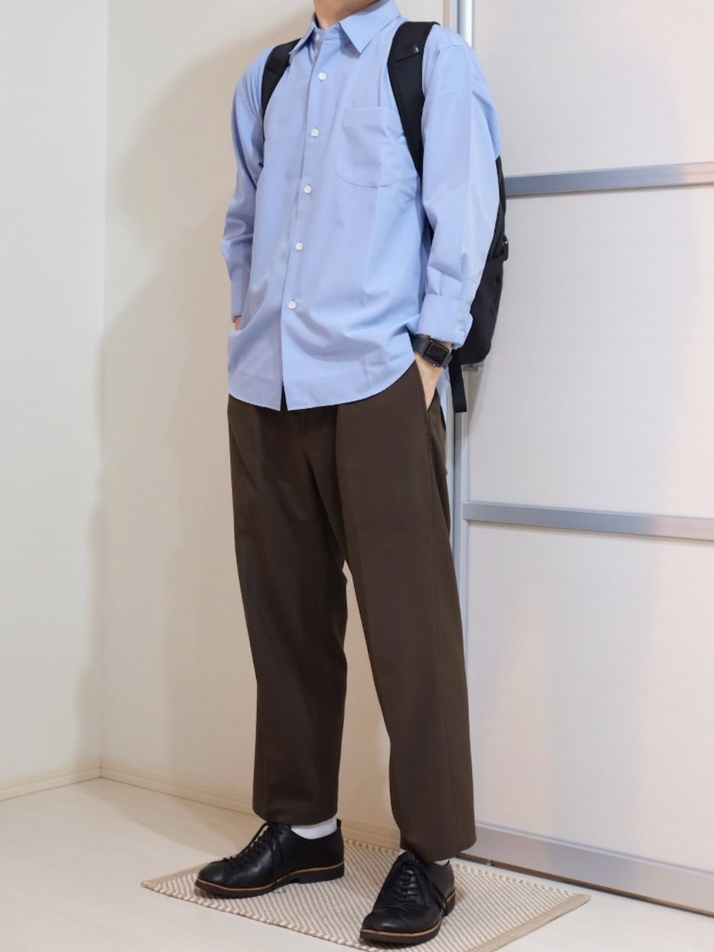 ブルー系のシャツ/ブラウス、ブラック系のバックパック/リュック、ブラウン系のパンツを着用したメンズの秋コーディネートの2枚目の写真