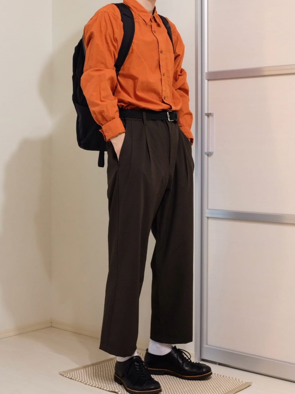 ブラウン系のその他パンツ、ブラック系のバックパック/リュック、オレンジ系のシャツ/ブラウスを着用したメンズの秋コーディネートの2枚目の写真