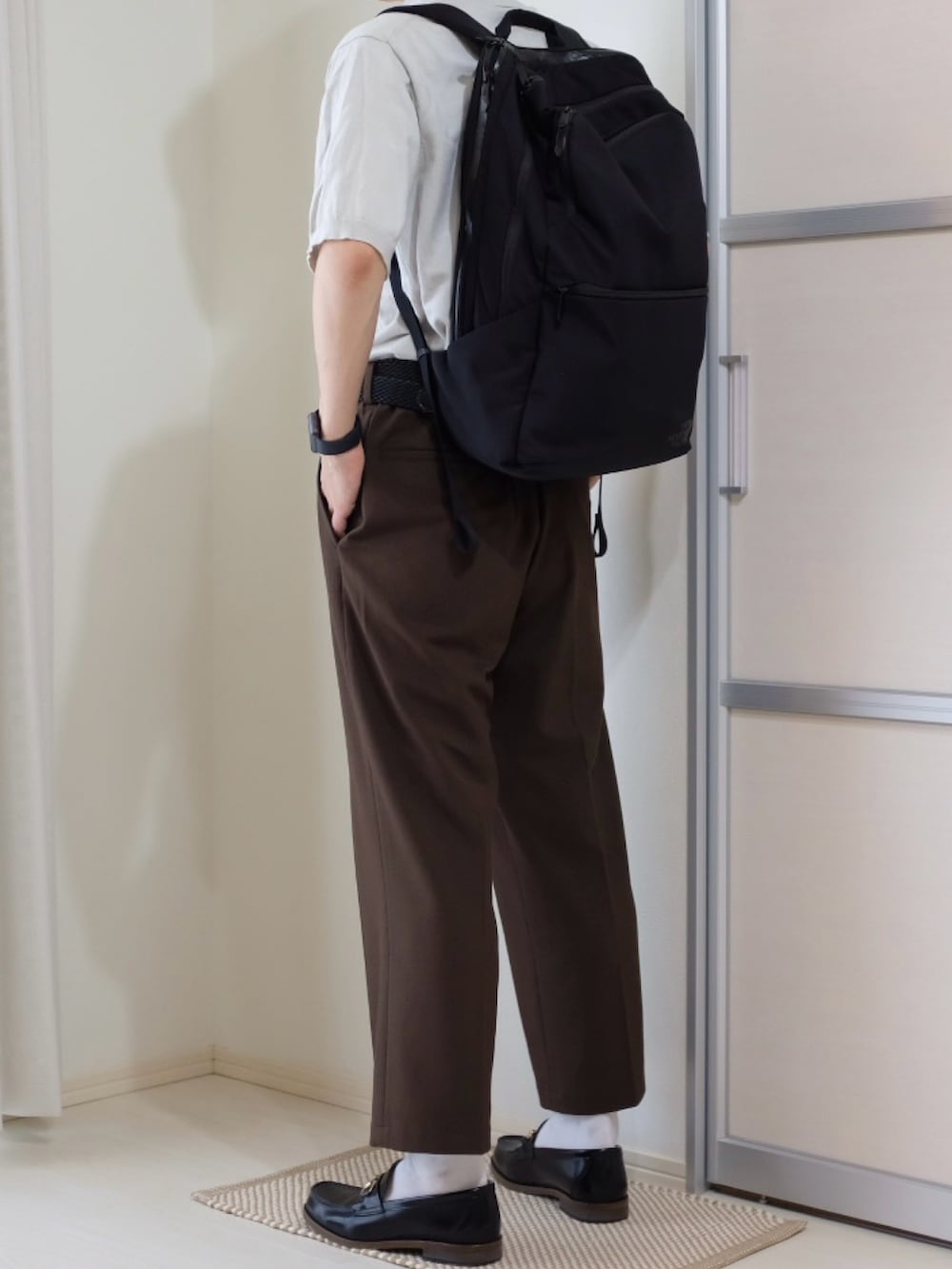 ブラウン系のパンツ、ホワイト系のトップス、ブラック系のバックパック/リュックを着用したメンズの秋コーディネートの2枚目の写真