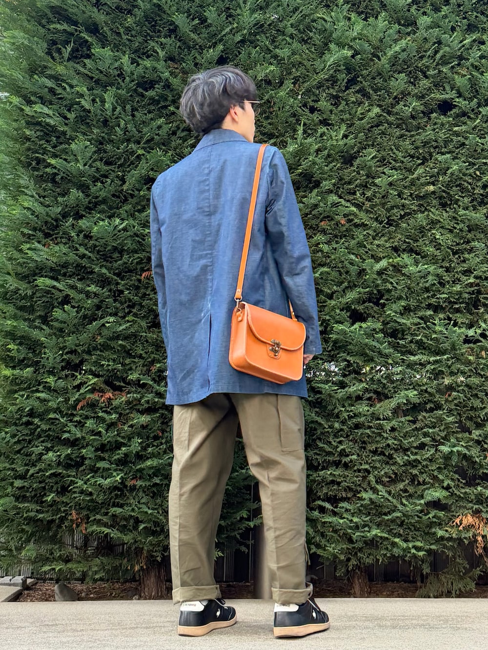 ベージュ系のベスト、ブルー系のその他アウター、オレンジ系のショルダーバッグを着用したメンズの秋コーディネートの3枚目の写真