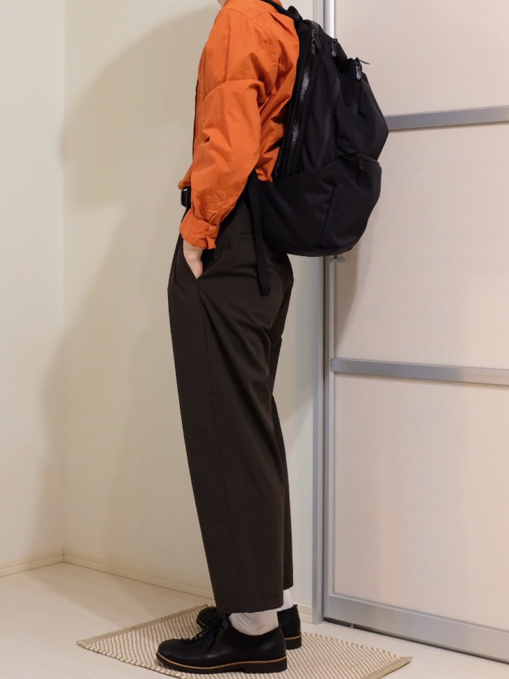 ブラウン系のその他パンツ、ブラック系のバックパック/リュック、オレンジ系のシャツ/ブラウスを着用したメンズの秋コーディネートの3枚目の写真